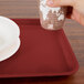 A hand holding a paper cup over a red Cambro tray.