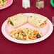A Classic Pink Creative Converting paper plate with pasta, salad, and tortilla wraps on a table.