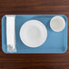 A blue tray with a white bowl and cup on it.