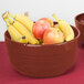 A Tablecraft maroon speckle cast aluminum fruit bowl filled with bananas and apples on a table.