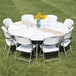 A Flash Furniture white plastic round folding table with white folding chairs and a vase of sunflowers.