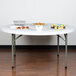 A Flash Furniture white plastic folding table with food on it.