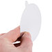 A hand holding a white oval foil lid.