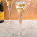 Two Chef & Sommelier flute glasses filled with champagne on a marble surface.