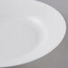 An Arcoroc white opal glass soup bowl with a white rim on a gray surface.