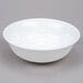 An Arcoroc white opal glass bowl on a gray surface.