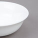 An Arcoroc white bowl with a white rim on a gray surface.