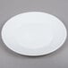 An Arcoroc white opal glass side plate with a white rim on a gray surface.