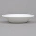 An Arcoroc white opal glass fruit dish on a gray surface.