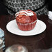 A red muffin with white frosting on a white Arcoroc narrow rim plate.