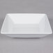A Tuxton TuxTrendz bright white square china bowl with a handle.