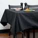 A table with a black Intedge rectangular tablecloth and a plate of food.