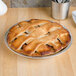 A pie in a Vollrath aluminum pie pan on a wood table.