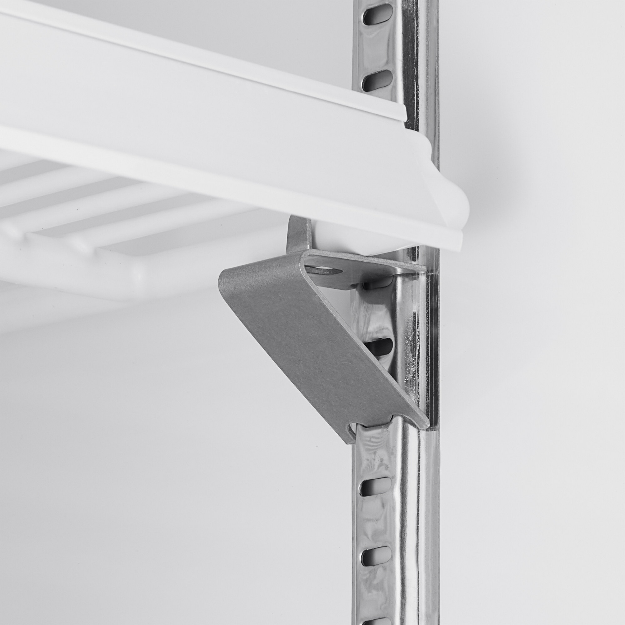 A close-up view of a metal shelf bracket supporting a white wire shelf inside a glass door merchandiser refrigerator.
