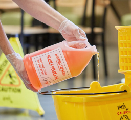 person pouring bottle of advantage chemicals into bucket