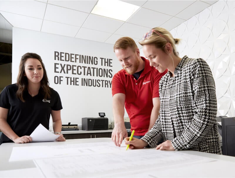 three people looking at paper on a desk