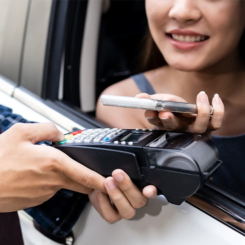 Asian customer makes a contactless mobile payment at a drive-thru