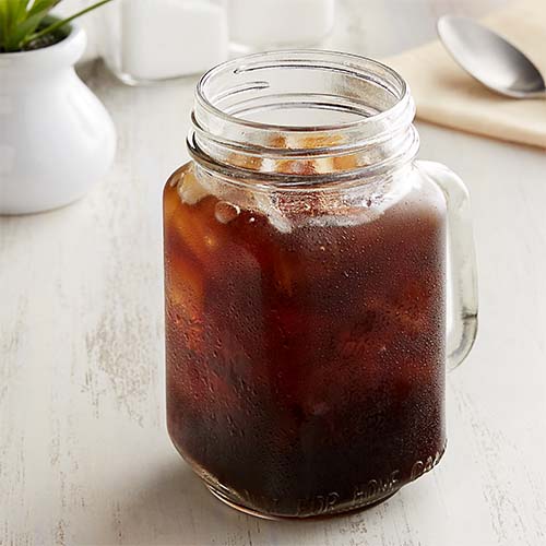 A glass mug filled with iced coffee.