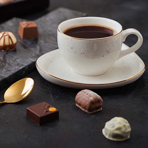 A cup of coffee and different kinds of chocolates.