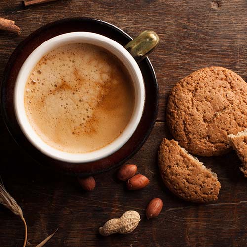 A cup of coffee from overhead and cookies next to the cup.