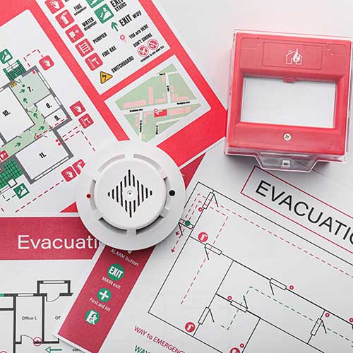 evacuation plans and smoke detector on white background