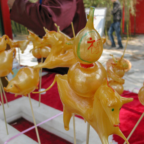 Sugar blown figures on sticks with Chinese writing on them.