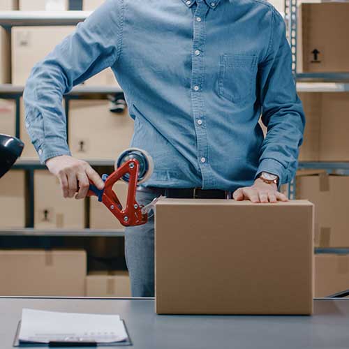 warehouse worker checks and seals cardboard box ready for shipment