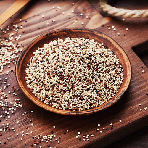 mixed quinoa in bowl on wooden kitchen board