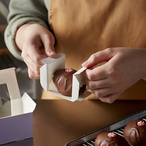 chocolatier packing a chocolate Easter egg into a chocolate box insert