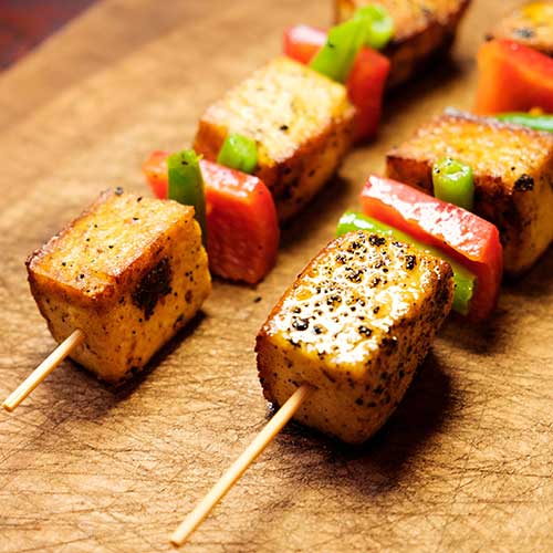 cubed tofu on skewer with tomato and herbs