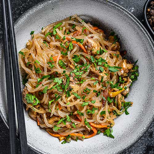 glass noodles with chicken on black slate background