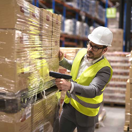 male warehouse worker using barcode scanner to analyze newly arrived goods