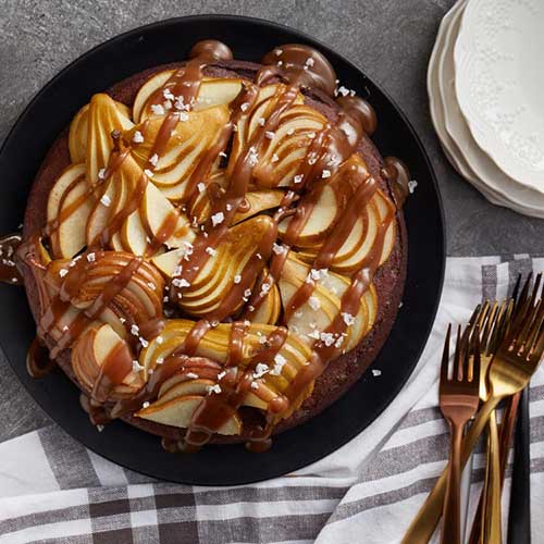 Chocolate Pear Cake in cast iron skillet topped with Caramel drizzle and flakes of sea salt