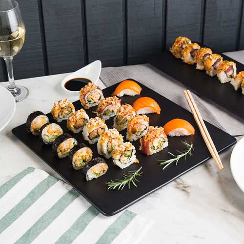 sushi rolls on black platter with sprigs of rosemary