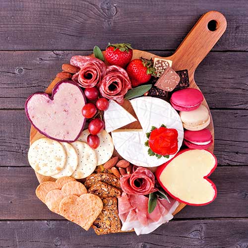 valentines day themed charcuterie board with a selection of cheeses appetizers and sweets
