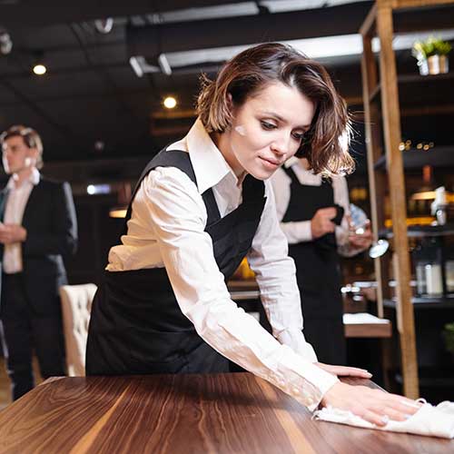 waitress wiping wooden table with cloth
