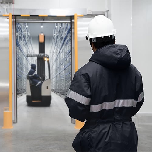 Cold storage warehouse employee in warm, protective clothing heading into the storage area