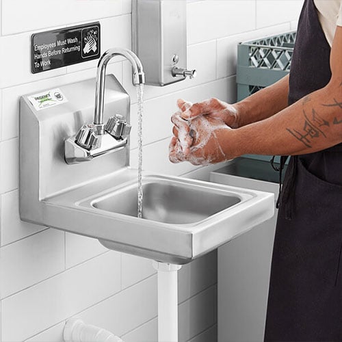 Server rubbing hands together with soap under running water