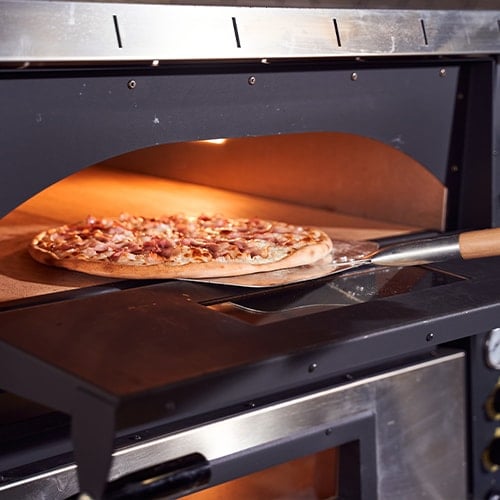 pizza peel sliding a pizza in to a pizza oven