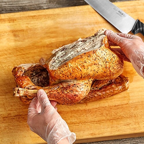 sprinkling seasoning from container on turkey before deep frying