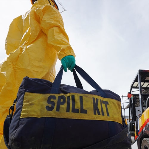 worker in protective suit carrying a spill kit bag