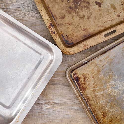 dull and discolored baking sheets next to a clean sheet