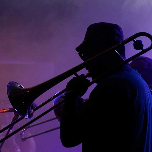 A jazz musician performs in the French quarter of New Orleans, Louisiana with smoke and neon lights in the background.