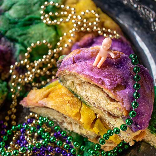 king cake with baby surrounded by mardi gras beads