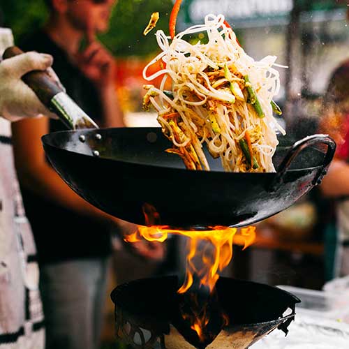 man cooks noodles on fire