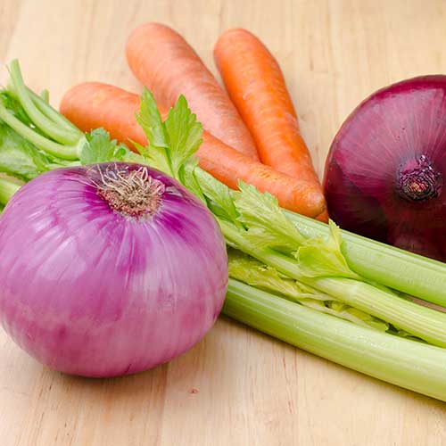 onions celery and carrots on a wooden table