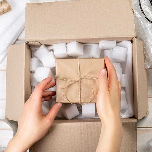 small brown paper package tied with brown string placed in packaging box