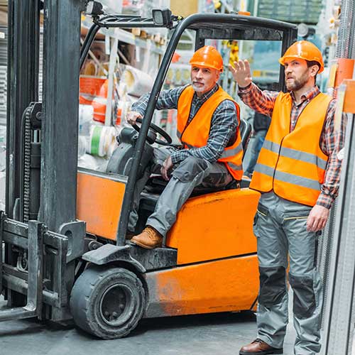 worker and his senior colleague working with forklift machine in storage