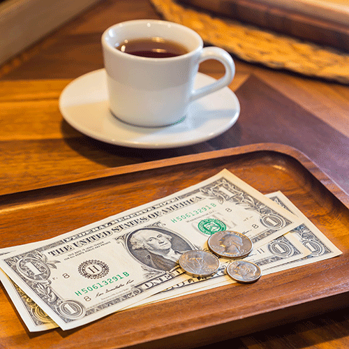 cash and coins in wooden tray on restaurant table