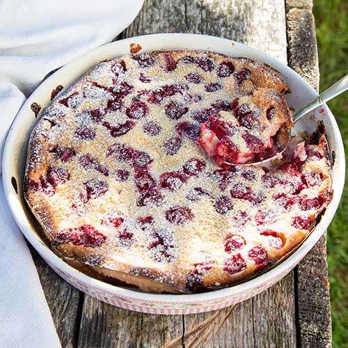 cherry clafoutis outside on wooden table